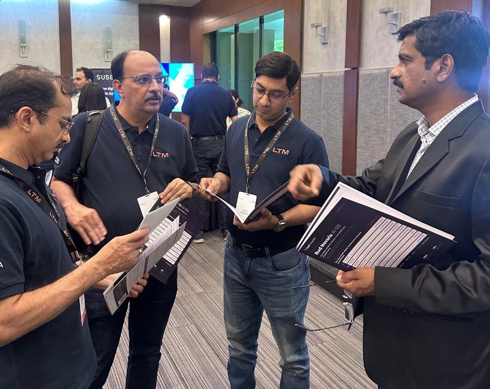 A Bud Ecosystem team member walks three LTM executives through a printed Bud Novaria AI OS brochure